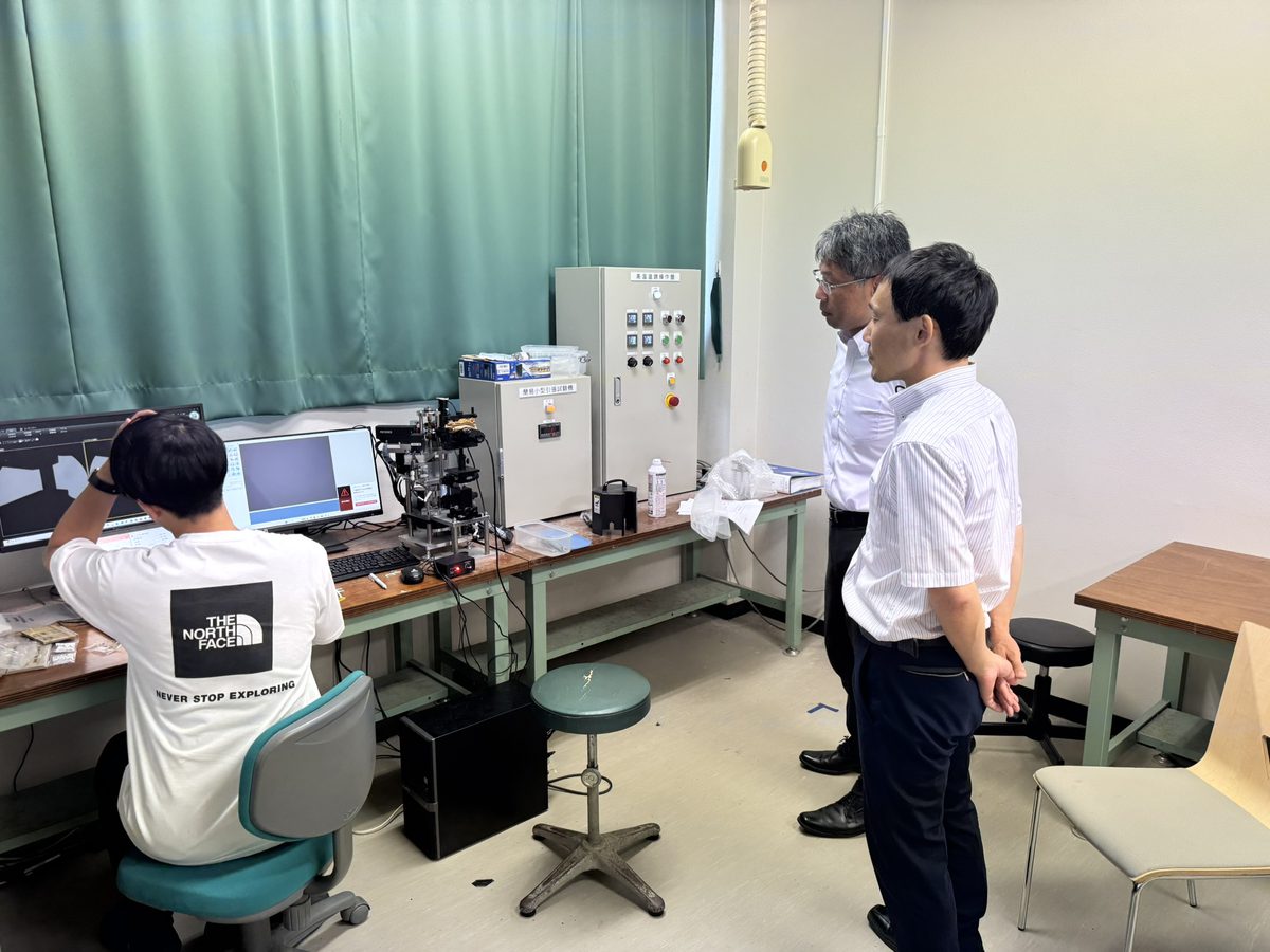 研究室の実験装置を見学する三菱重工の木村さんと石井さん