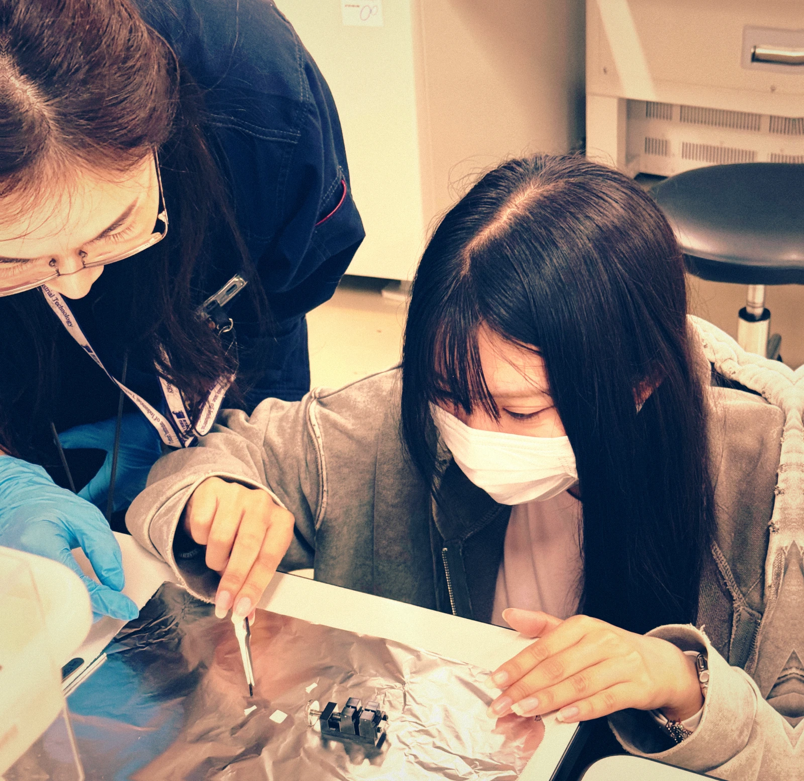 女子学生がピンセットで試料をつまみにいく瞬間を捉えた実験室の写真